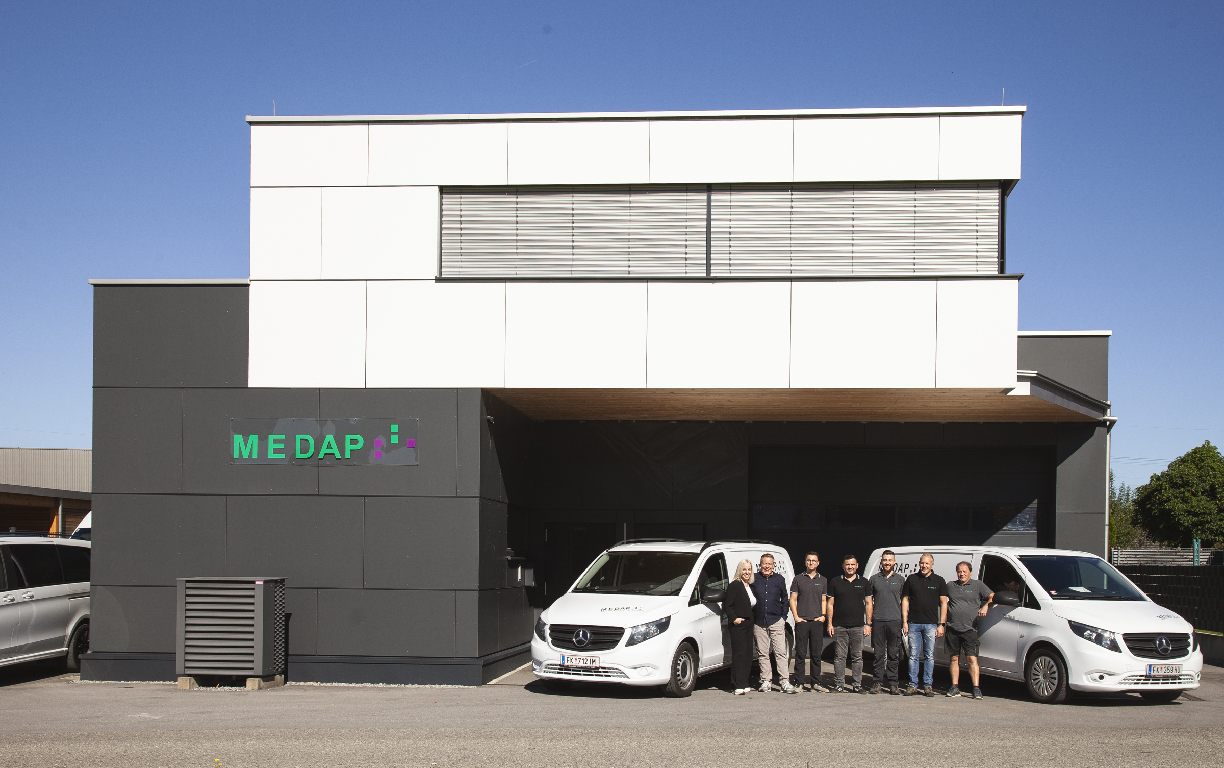 Das MEDAP Team vor dem modernen Firmengebäude und Firmenautos